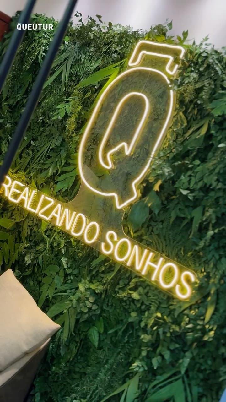 Letreiro neon "Realizando Sonhos" no lounge da Casa Azul