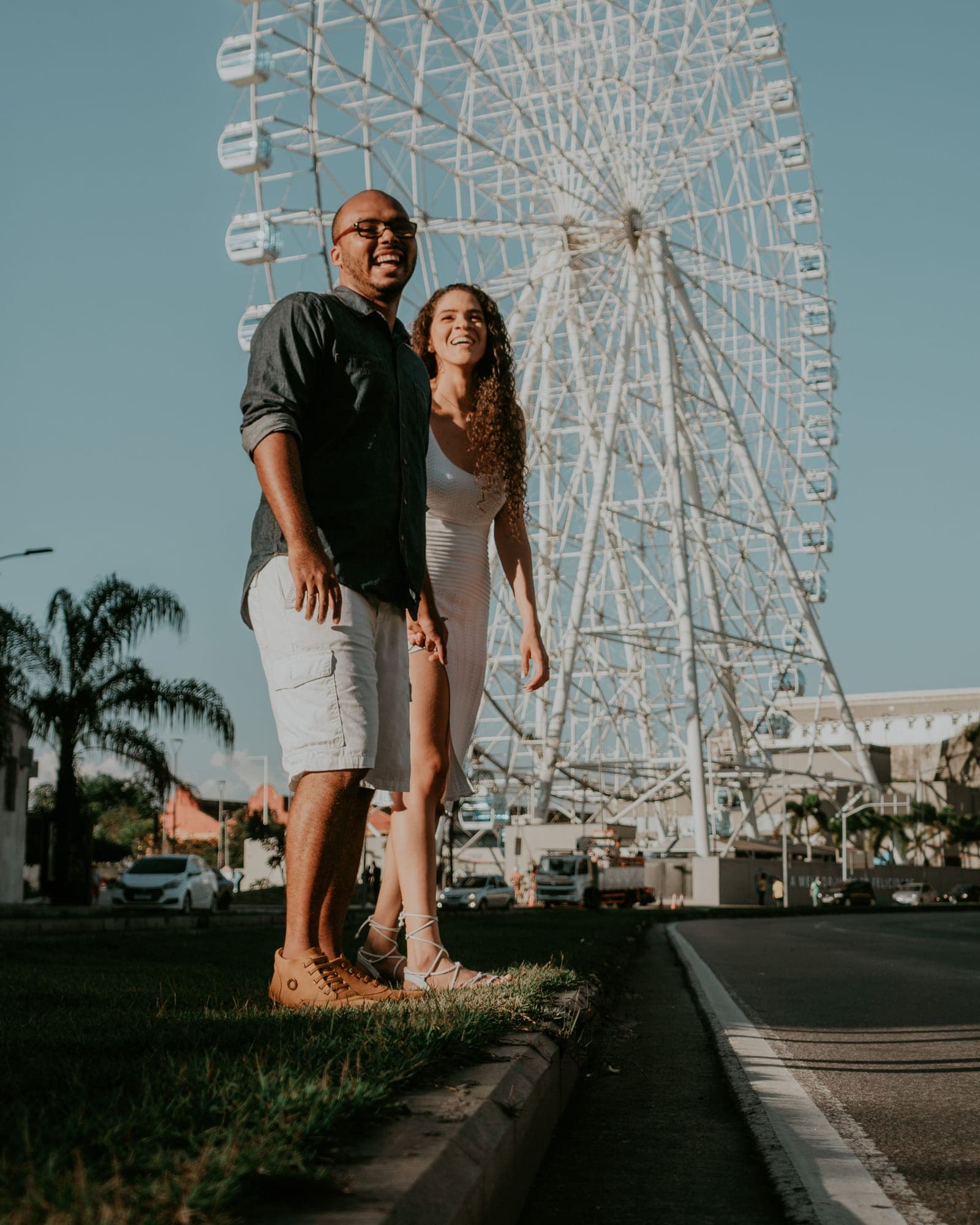 Casal sorrindo em frente à roda-gigante