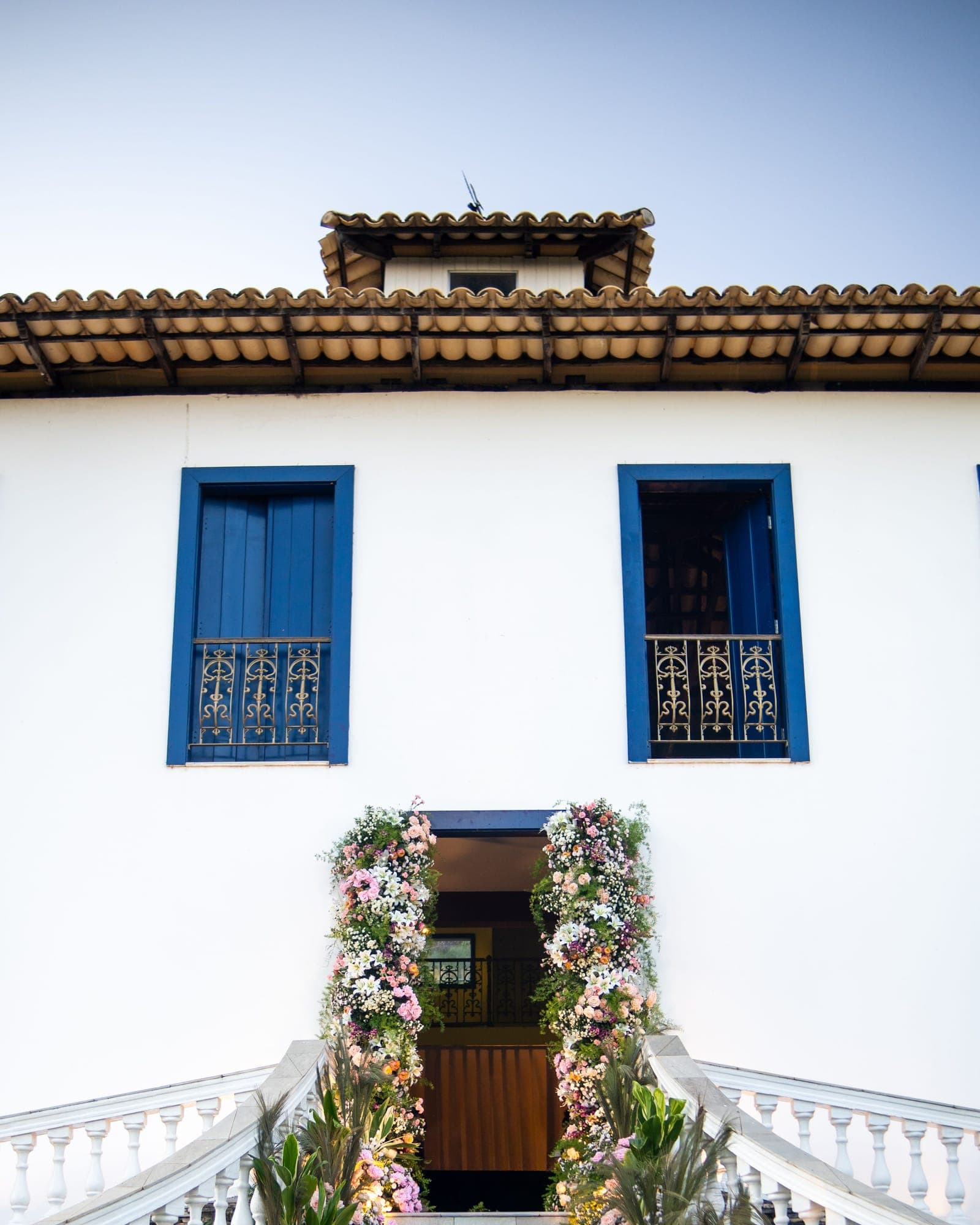 Entrada ornamentada com flores e janelas azuis