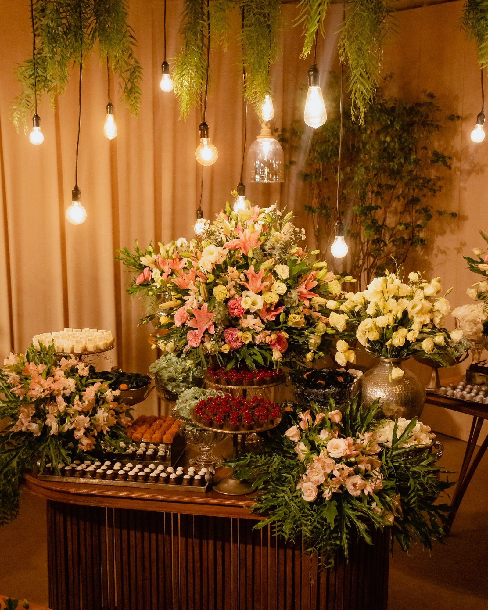 Mesa de doces com arranjos de flores