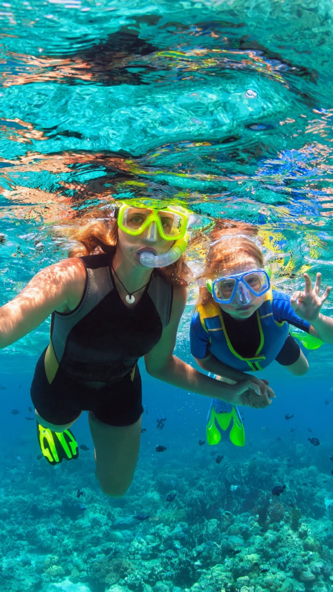 Mãe e filho mergulhando de snorkel em piscina natural cristalina